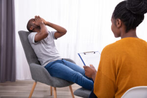 Female Psychologist With Clipboard Sitting Near Young Man