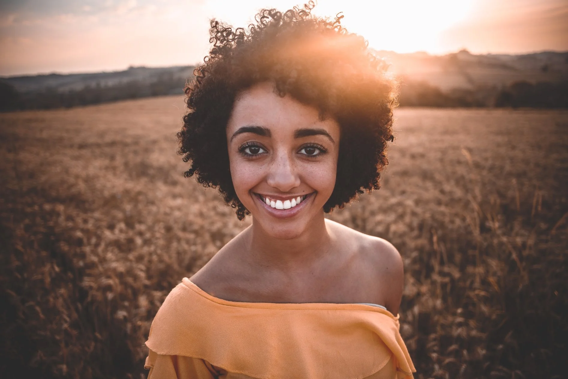 Woman smiling with sunrise at the back everyday life is achievable with outpatient care & holds significant advantages over sober living homes
